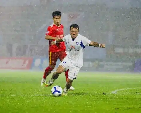 Cầu thủ Khánh Hòa áo trắng dẫn bóng trong mưa lớn ở trận gặp CAND